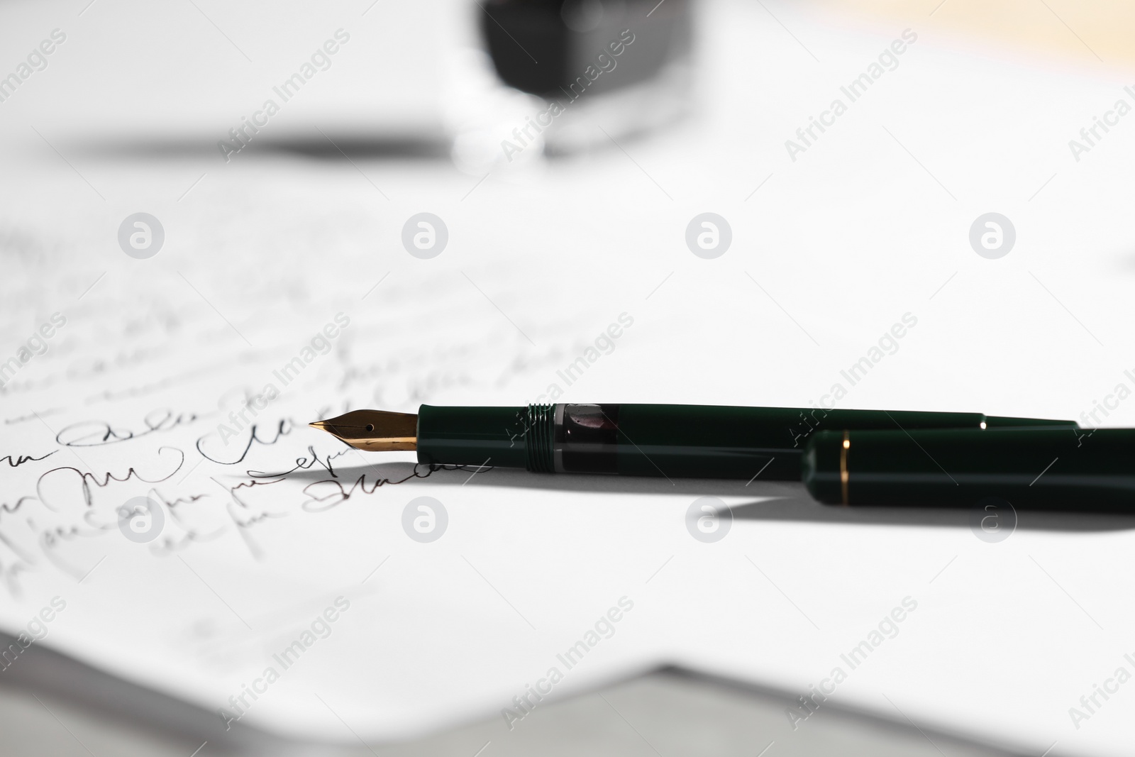 Photo of Elegant fountain pen and handwritten letter on table, closeup