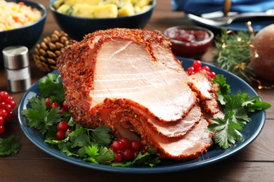 Delicious Christmas ham served with garnish on wooden table