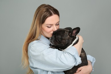 Woman hugging cute French Bulldog on grey background