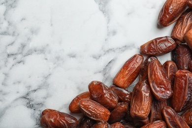 Photo of Frame made of sweet dried date fruits on marble background, top view with space for text