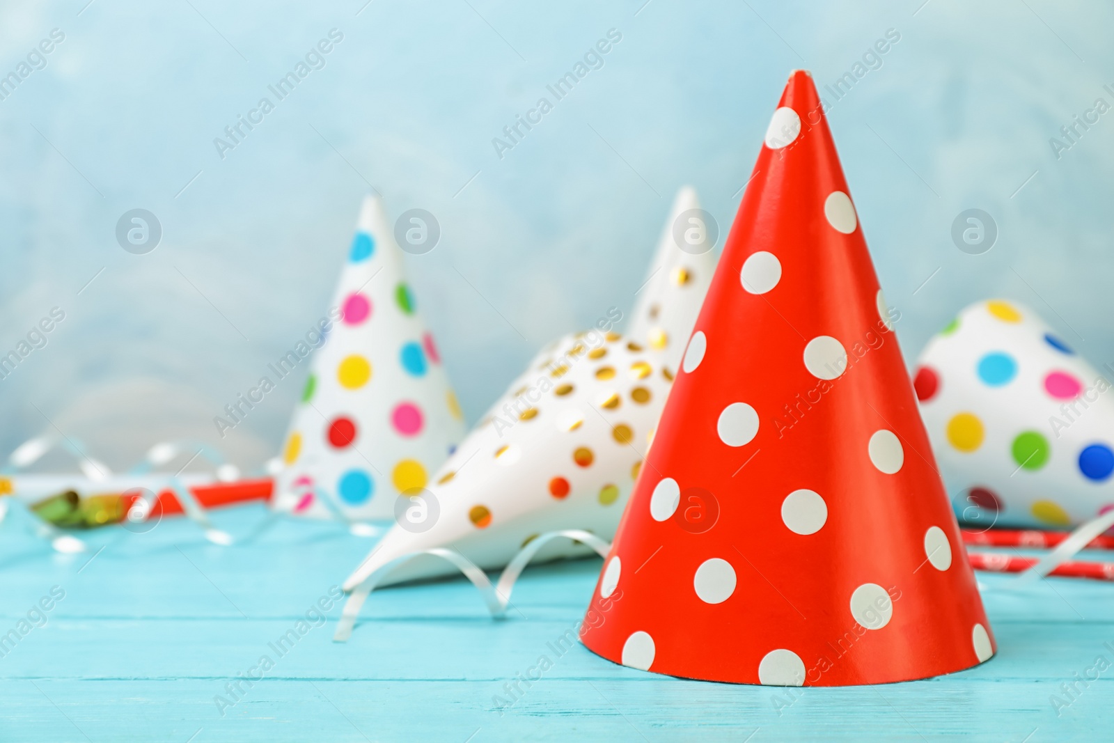 Photo of Birthday party caps on table against color background