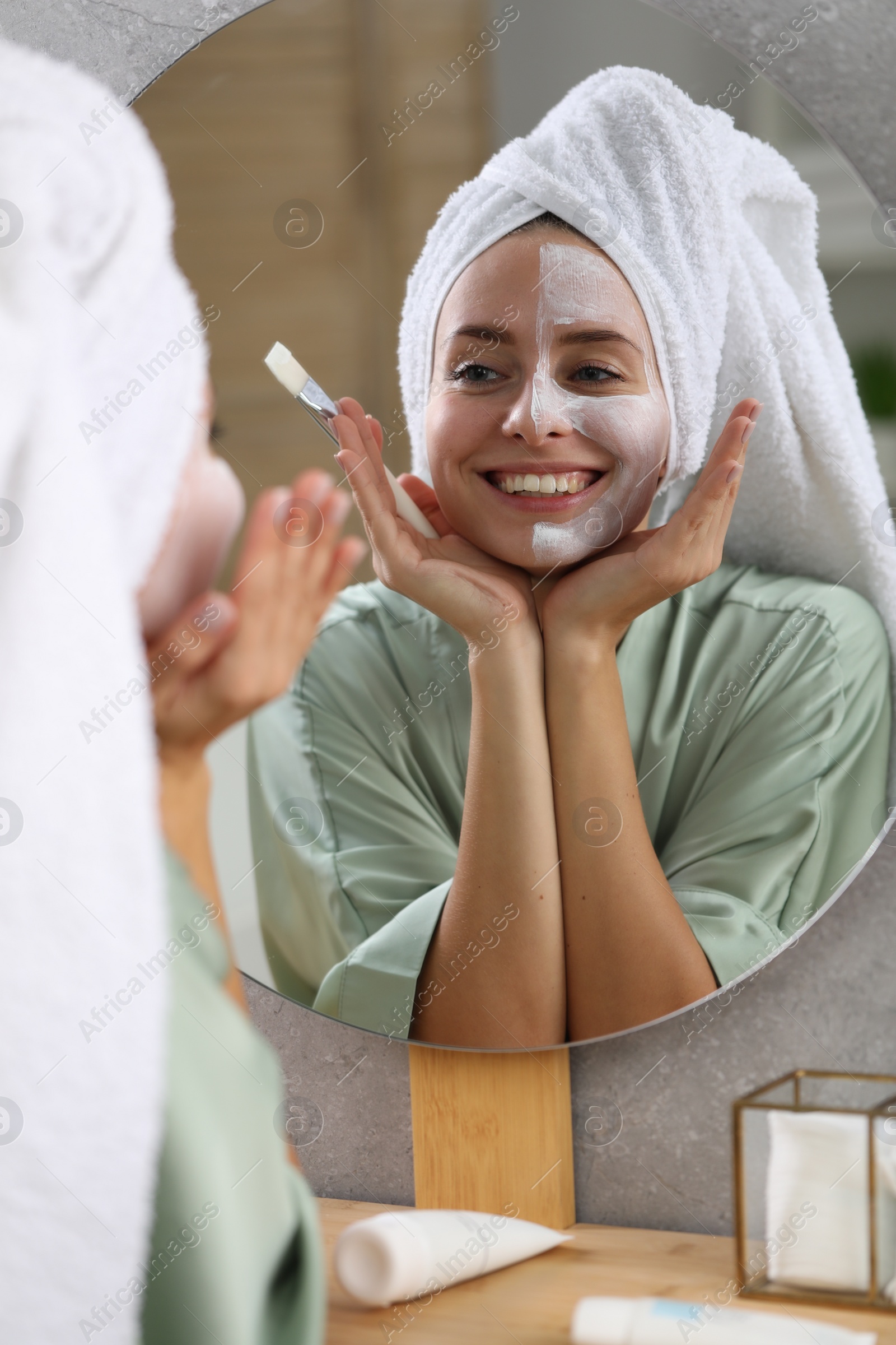 Photo of Woman with face mask in front of mirror indoors. Spa treatments