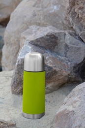 Metallic thermos with hot drink on stone, space for text