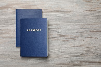 Photo of Blank blue passports on wooden table, flat lay with space for text