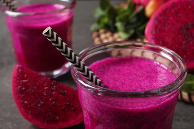 Photo of Glass of tasty pitahaya smoothie with straw on table, closeup view