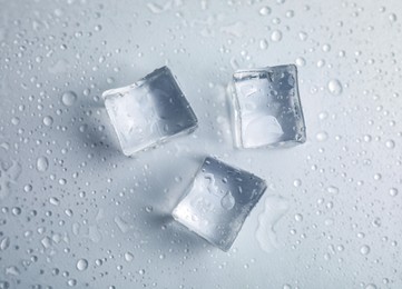 Ice cubes with water drops on white background, top view