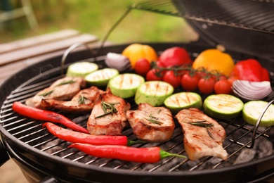 Photo of Modern grill with meat and vegetables outdoors, closeup