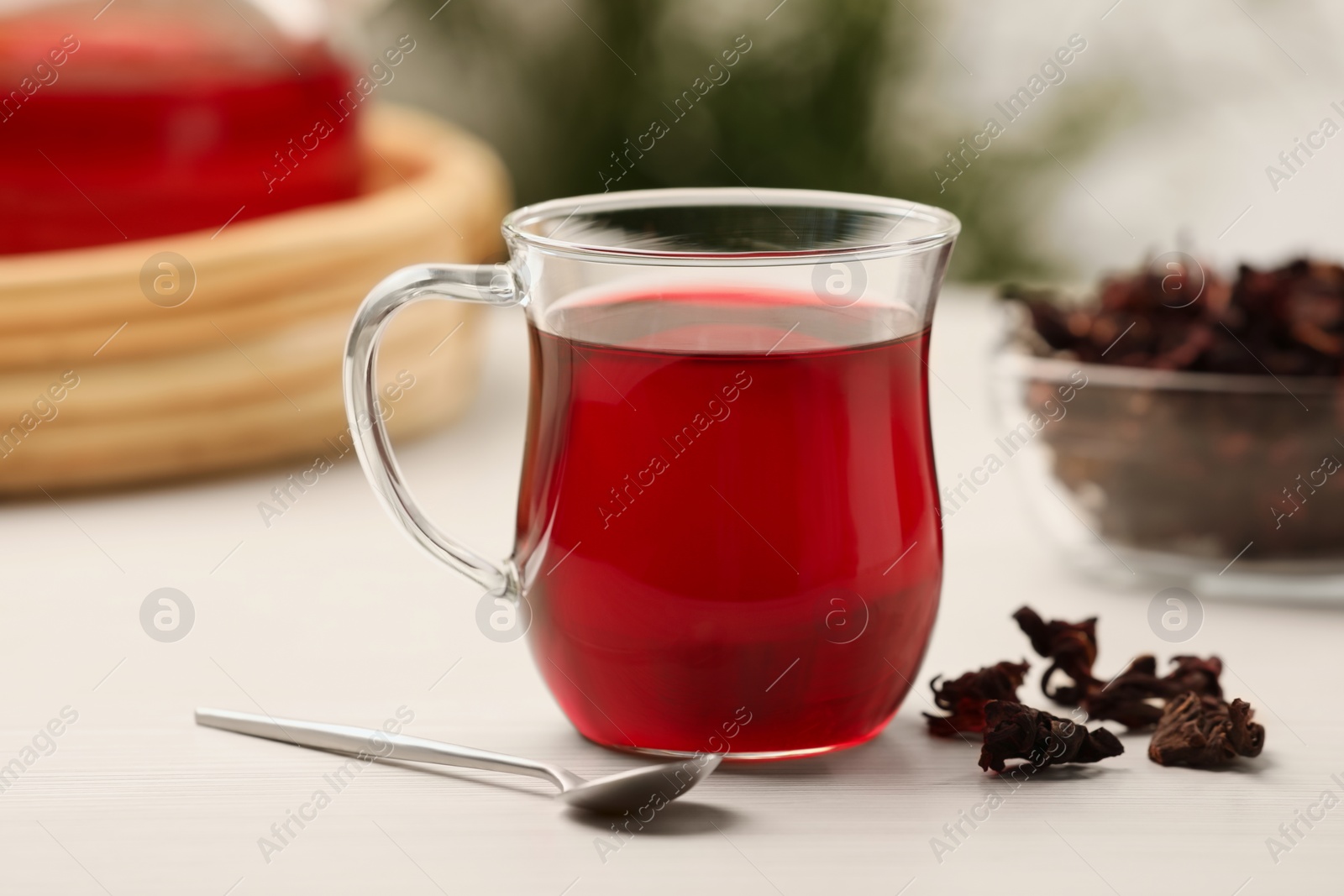 Photo of Delicious hibiscus tea and dry flowers on white wooden table