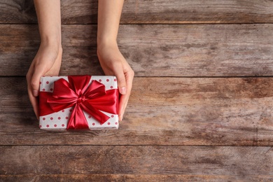 Photo of Woman with beautiful gift box on wooden background, top view