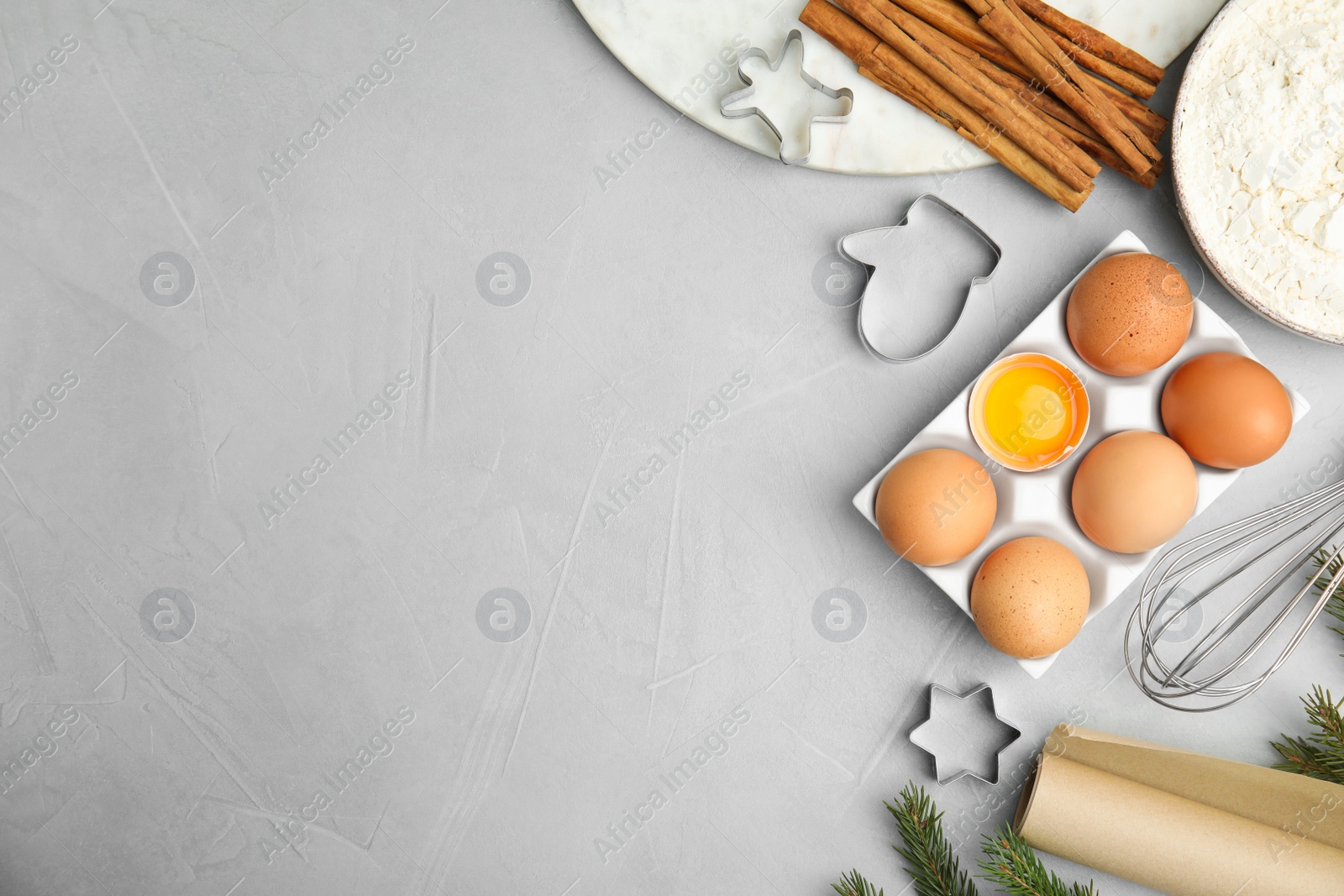 Photo of Flat lay composition with cookie cutters and ingredients on light grey table, space for text. Christmas biscuits