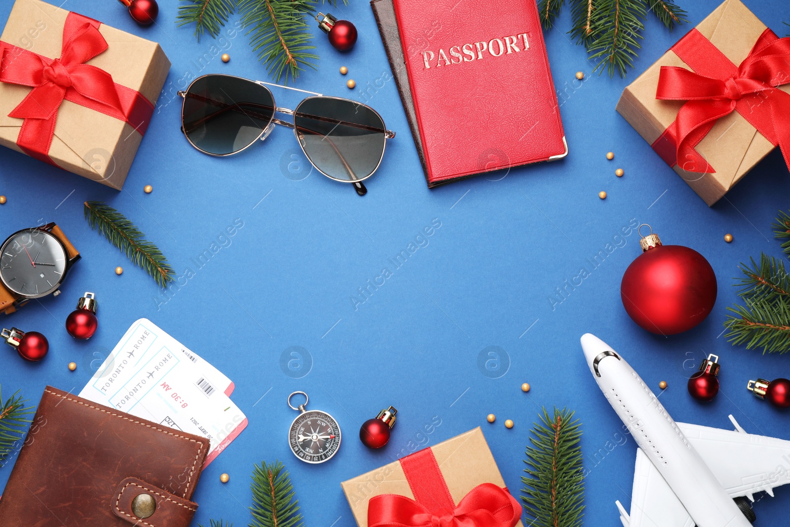 Photo of Frame with toy airplane, festive decor, gift boxes and space for text on blue background, flat lay. Christmas vacation