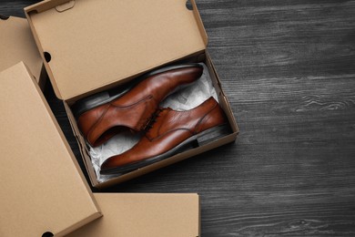 Photo of Stylish men's shoes and cardboard boxes on wooden floor, flat lay. Space for text
