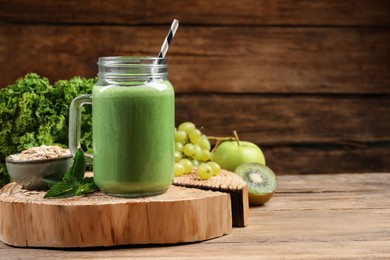 Photo of Mason jar of fresh green smoothie and ingredients on wooden table, space for text
