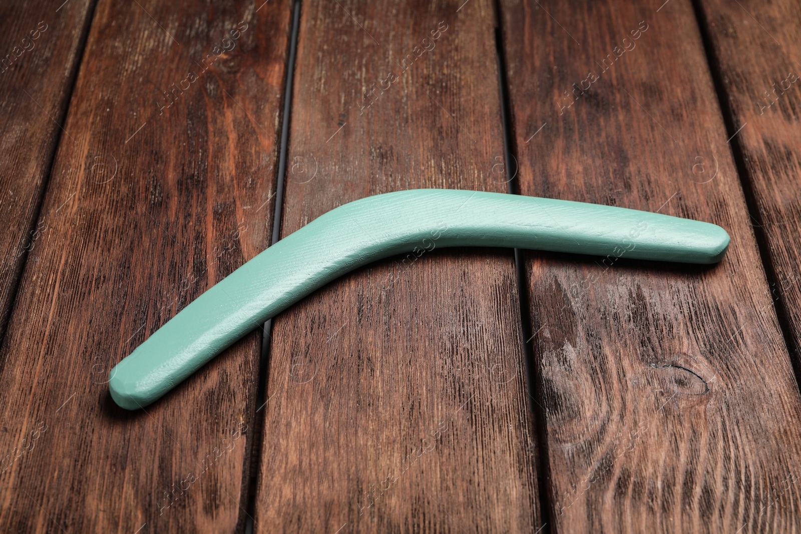 Photo of Turquoise boomerang on wooden background. Outdoors activity