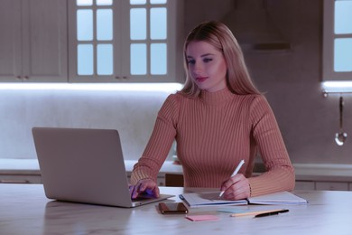 Photo of Home workplace. Woman working on laptop at marble desk in kitchen