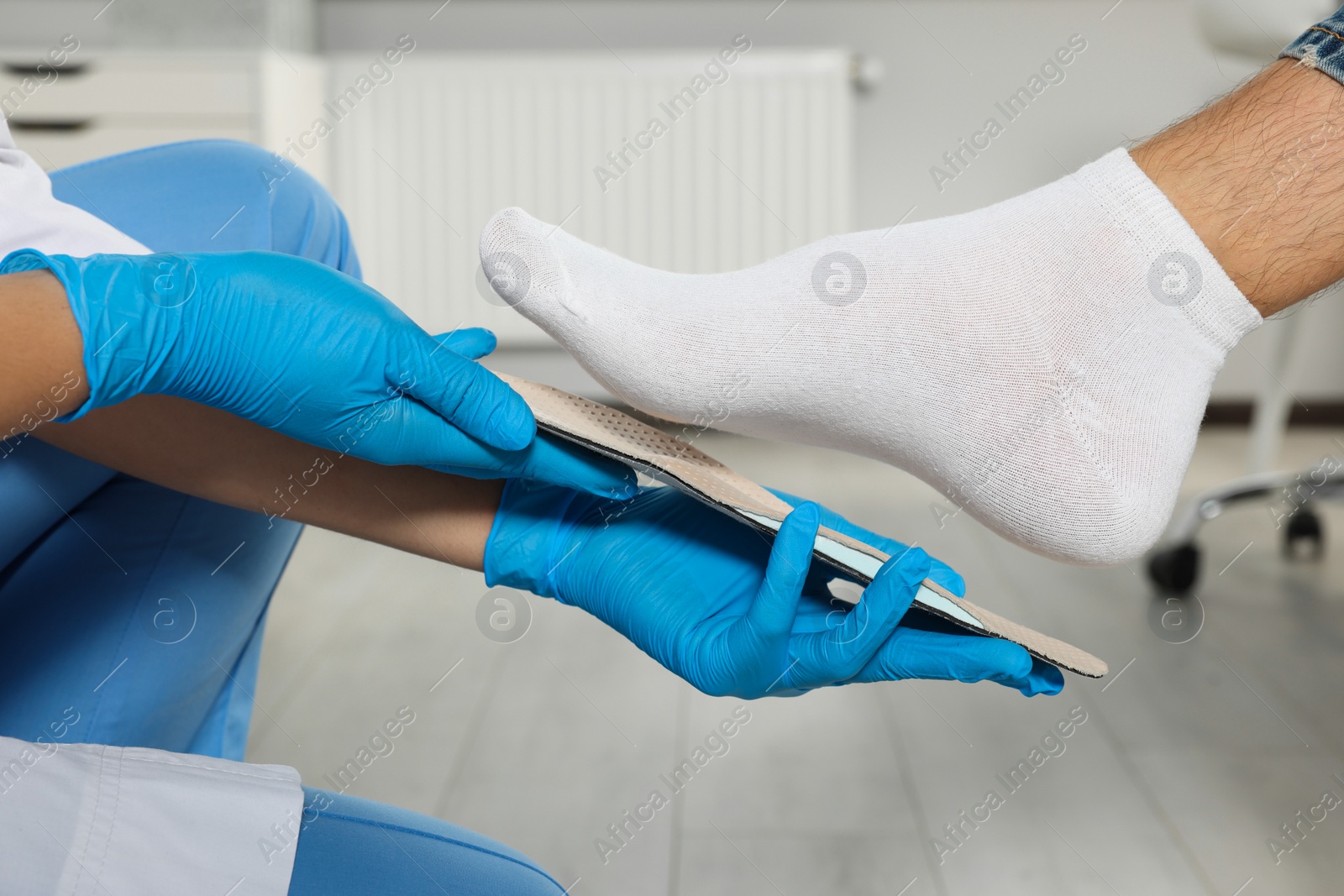 Photo of Orthopedist fitting insole to patient's foot in hospital, closeup