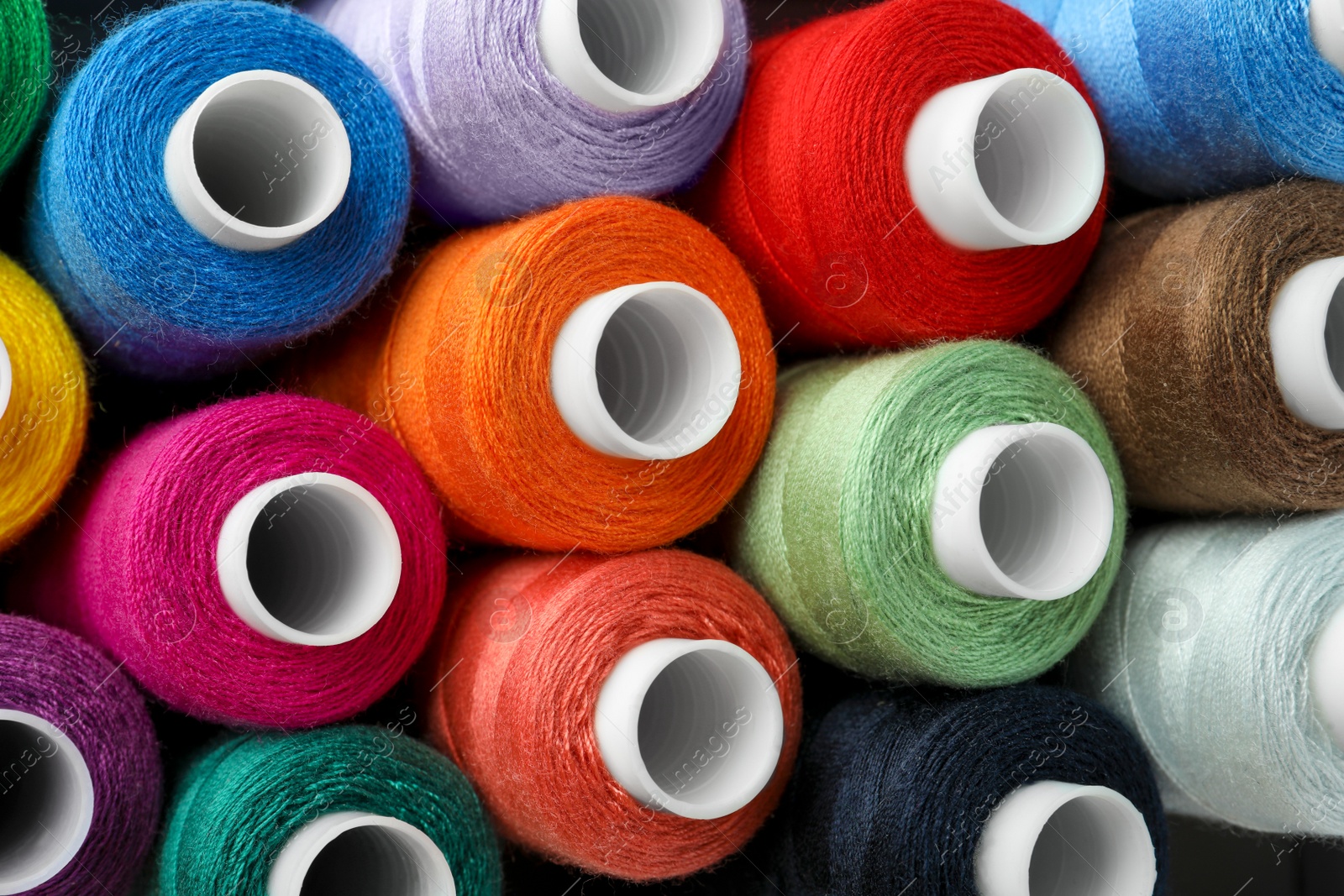 Photo of Top view of colorful sewing threads as background, closeup