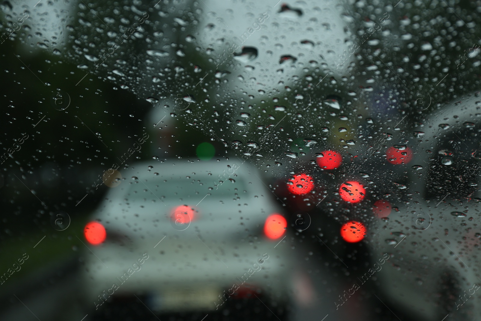 Photo of Blurred view of road through wet car window. Rainy weather