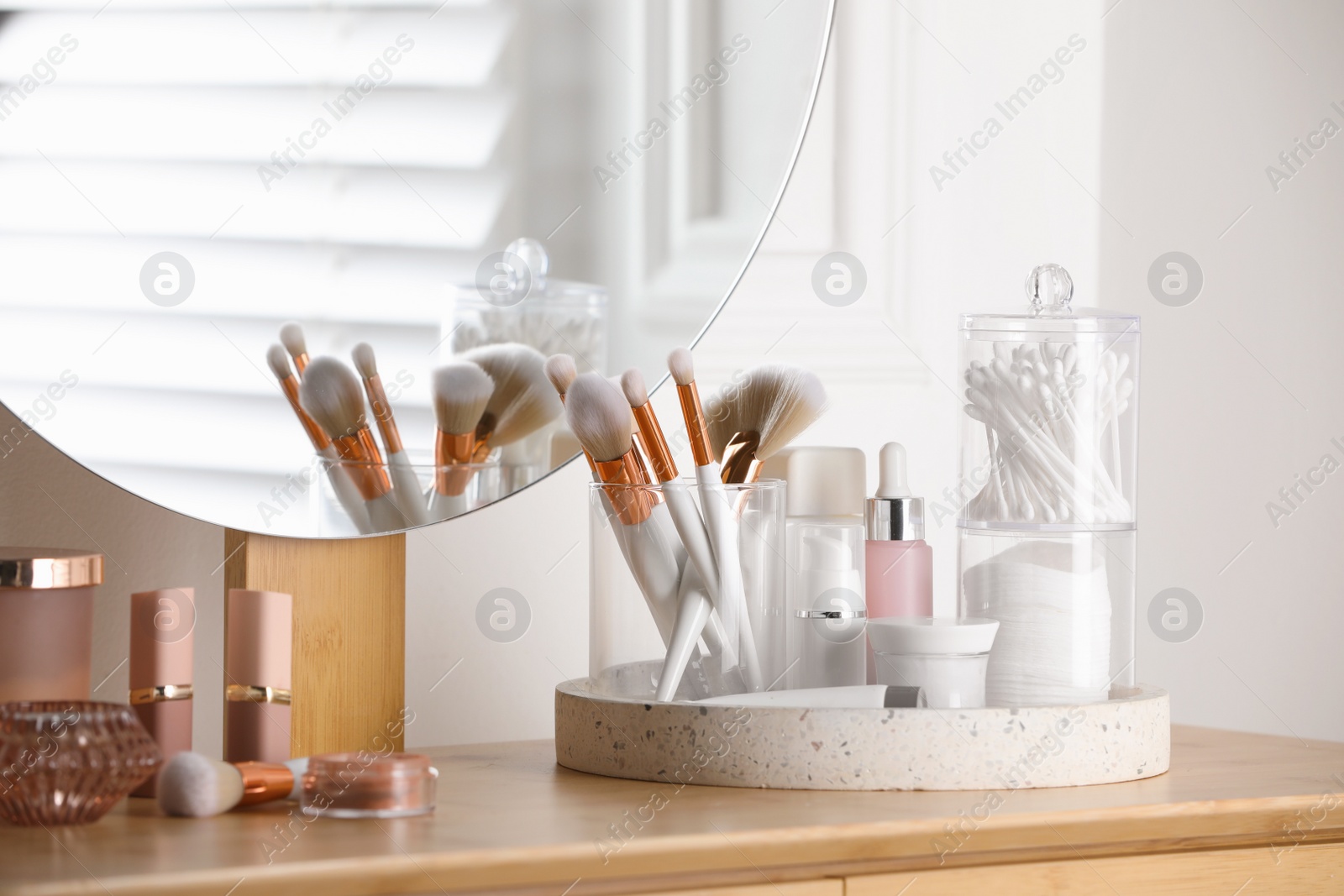 Photo of Containers with cotton swabs and pads near cosmetic products on dressing table