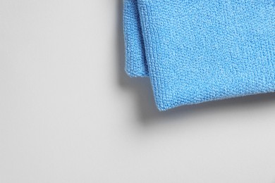 Photo of Soft folded light blue towel on light grey background, top view. Space for text