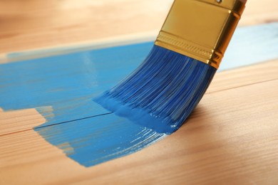 Photo of Applying blue paint onto wooden surface, closeup