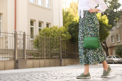Photo of Woman with stylish green bag on city street, closeup. Space for text