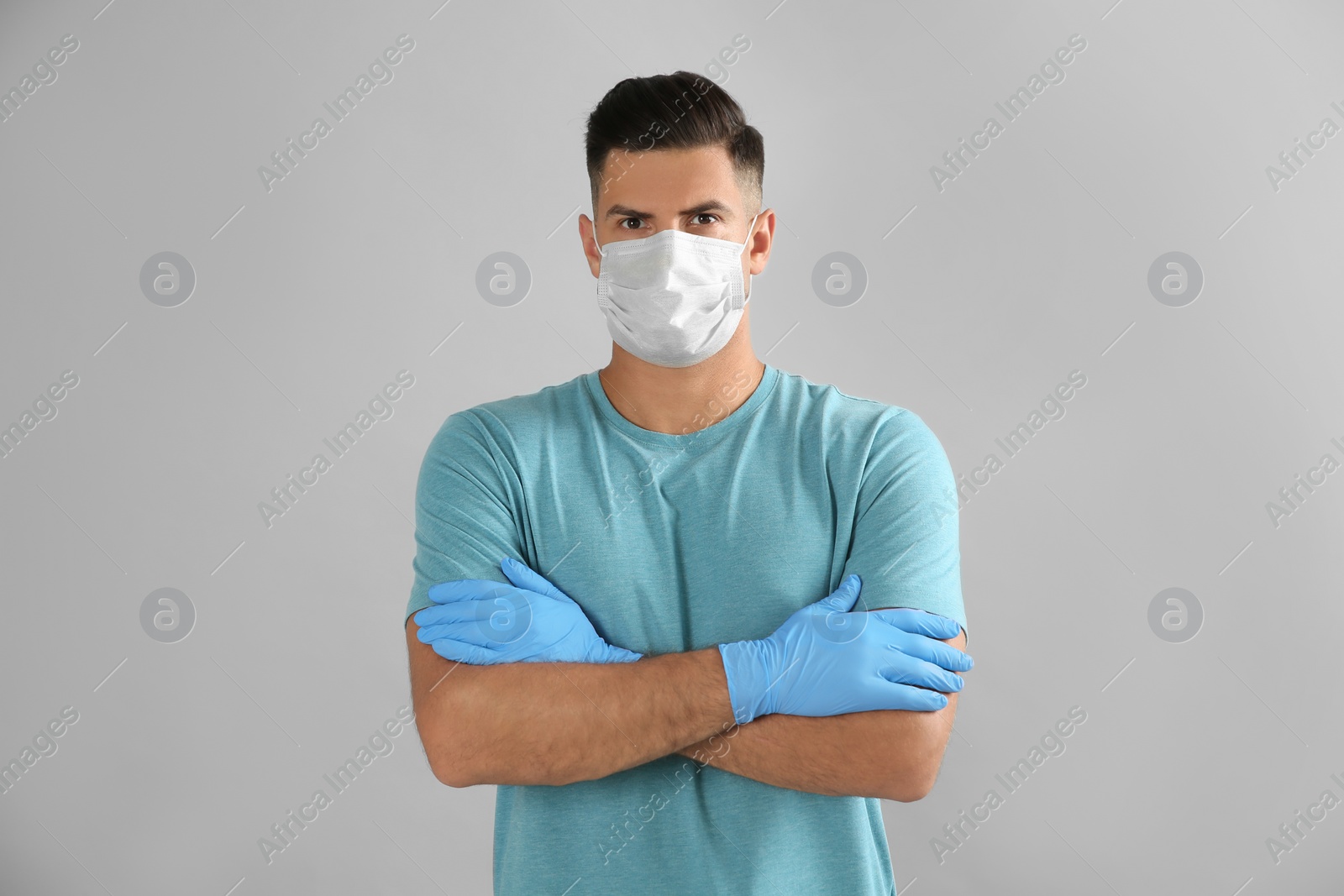 Photo of Man wearing protective face mask and medical gloves on grey background