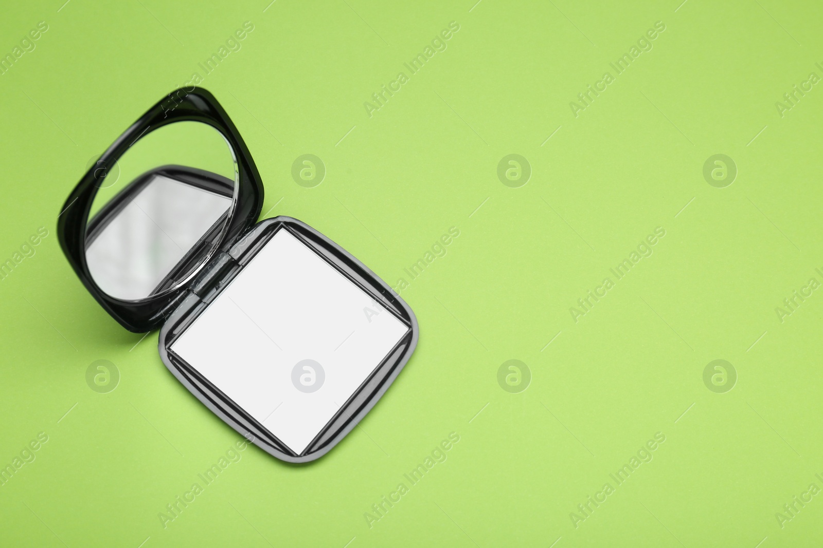 Photo of Stylish cosmetic pocket mirror on light green background, top view. Space for text