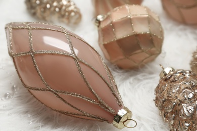Photo of Collection of beautiful Christmas tree baubles on white faux fur, closeup