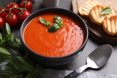 Photo of Delicious tomato cream soup in bowl served on grey table