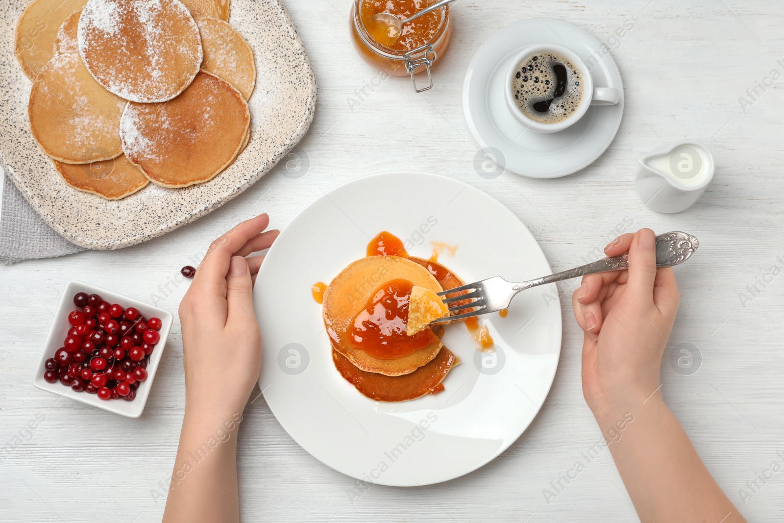 Photo of Woman eating delicious pancakes with jam at table