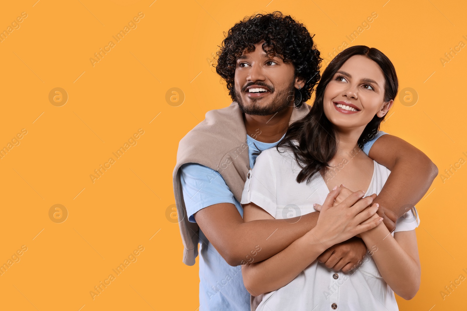 Photo of International dating. Happy couple hugging on yellow background, space for text