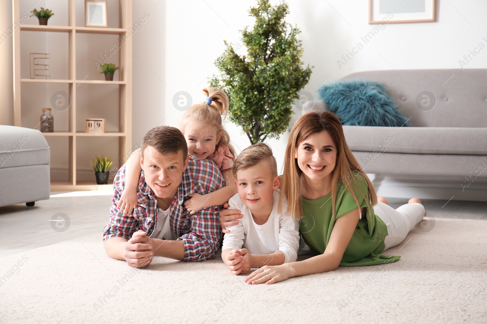 Photo of Happy family lying on cozy carpet at home