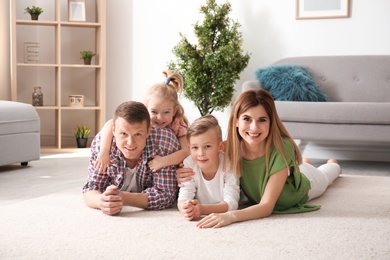 Happy family lying on cozy carpet at home