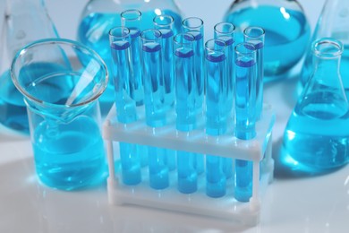 Photo of Laboratory glassware with blue liquid on light background