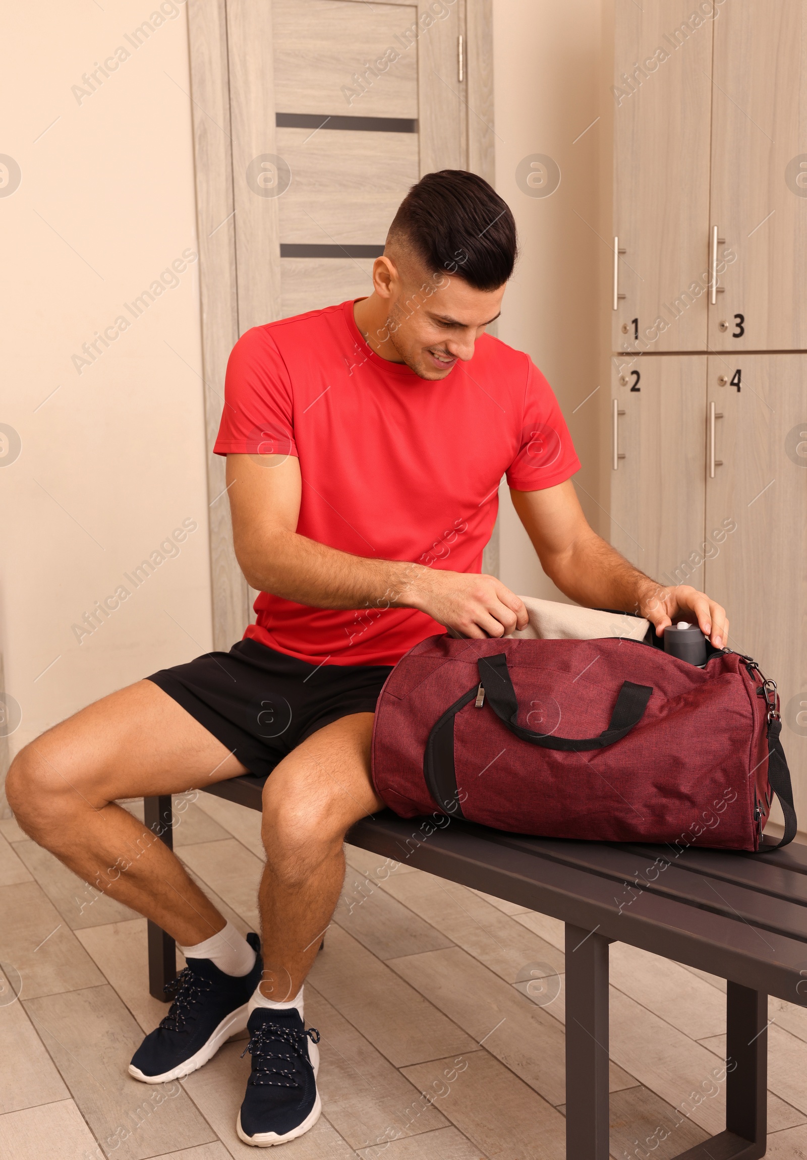 Photo of Handsome man with sports bag in locker room