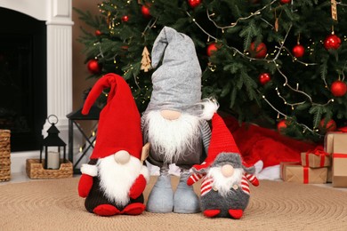Photo of Cute decorative gnomes on floor near Christmas tree at home