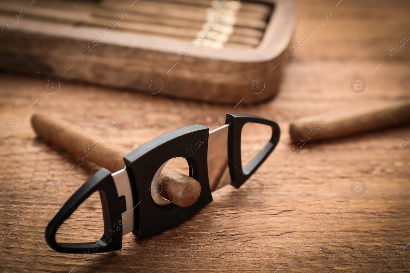 Photo of Cigars with guillotine cutter on wooden table