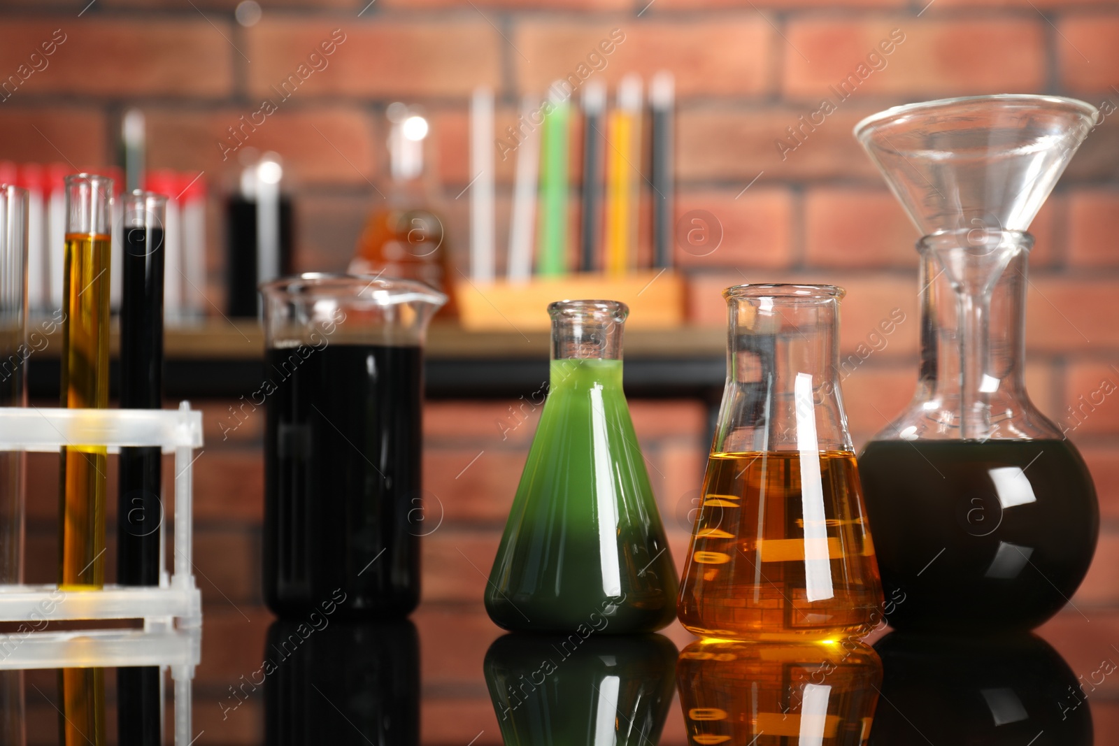 Photo of Laboratory glassware with different types of oil on mirror table indoors, closeup