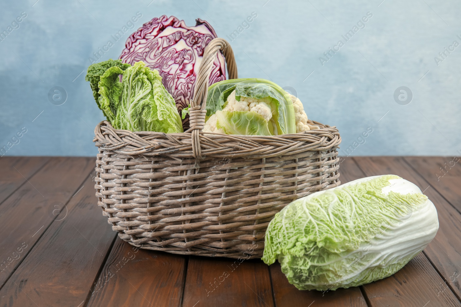 Photo of Basket with tasty cabbages on wooden table