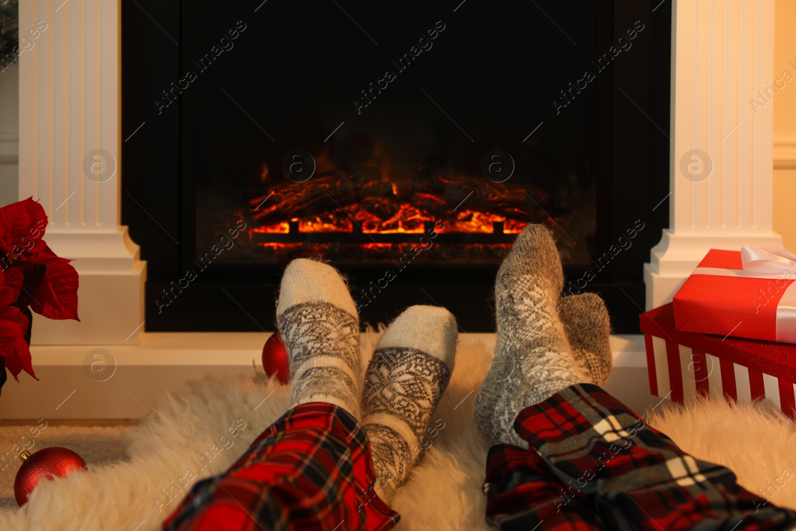 Photo of Couple in warm socks resting near fireplace at home, closeup