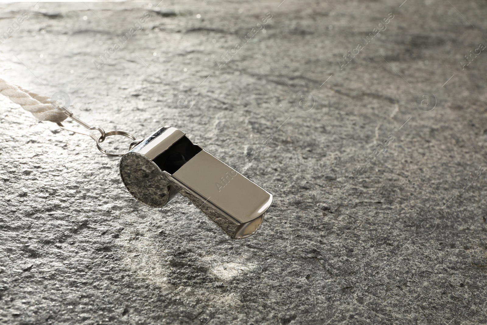 Photo of Referee equipment. Metal whistle on grey textured background, closeup and space for text