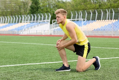 Photo of Man in sportswear suffering from knee pain at soccer field