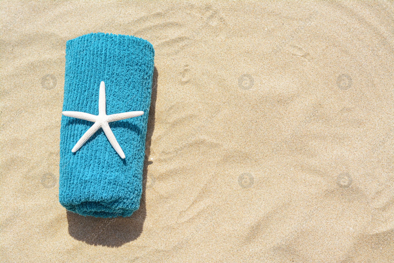 Photo of Towel with starfish on sand outdoors, top view and space for text. Beach accessory