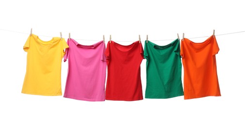 Different bright t-shirts drying on washing line against white background