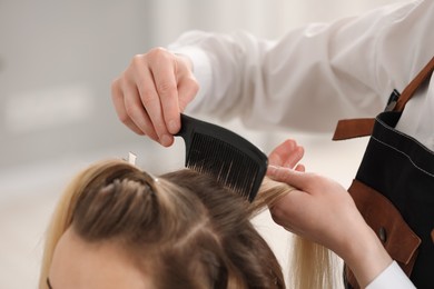 Photo of Hair styling. Professional hairdresser combing woman's hair in salon, closeup
