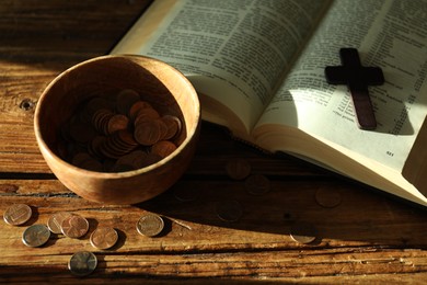 Donate and give concept. Bowl with coins, cross and Bible on wooden table