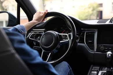 Woman holding steering wheel while driving her car, closeup