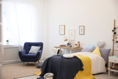 Modern teenager's room interior with bed and armchair