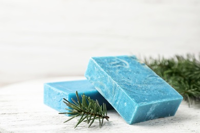 Photo of Handmade soap bars and fir branch on table